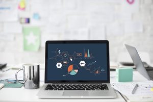 Laptop sitting on an office desk with infographics regarding digital marketing